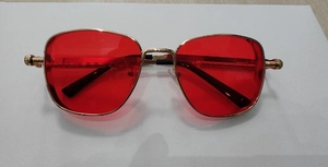 Detail of red lenses and gold metallic frame with textured screw thread patterns