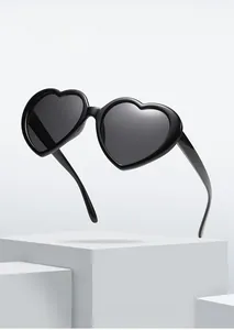Detailed view of heart-shaped black polarized sunglasses on white geometric display stand