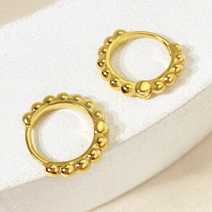 Macro detail of gold beaded hoop earrings with high-polish finish and minimalist texture