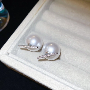 Macro detail of elegant pearl earrings with silver bar and sparkling cubic zirconia stones