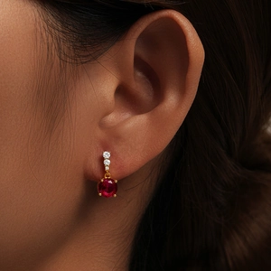 Detail of red gemstone earring with gold setting and white diamond accents on model