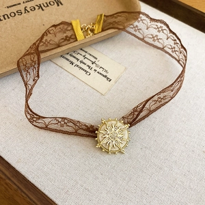 Close-up of vintage brown lace choker with a golden sun pendant and crystal details
