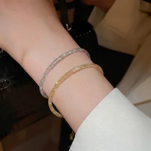 Ensemble élégant de bracelets joncs dorés et argentés avec texture maillée au poignet