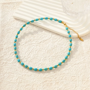 Elegant beaded necklace with turquoise stones and golden accents on a minimalist white stand