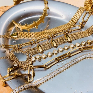 Macro shot of gold bracelets with sparkling zircons in a metal tray with water droplets
