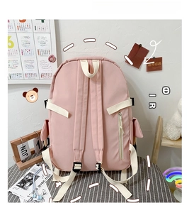 Rear view of pink canvas backpack showing security zipper pocket and cream straps