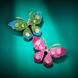 Macro detail of butterfly brooches featuring gradient rhinestones and cat eye stones