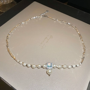 Detailed macro view of square light blue pendant with white pearls and silver beaded chain