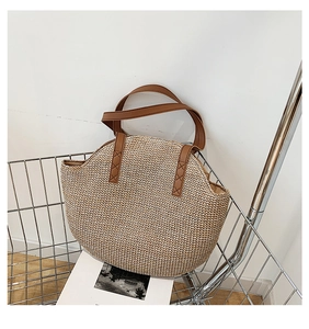 Detail of handwoven straw tote bag texture and brown faux leather handle stitching