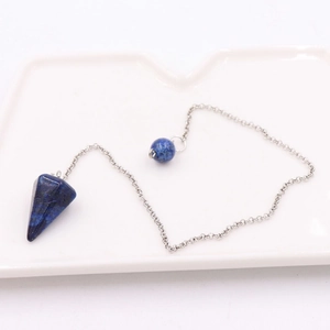 Close-up of lapis lazuli conical pendulum pendant with silver chain on white tray