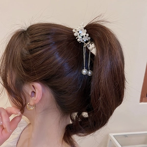 Detail of elegant flower hair claw clip with pearls and tassels worn on high ponytail
