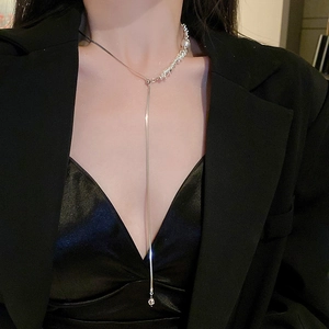 Detail of silver Y-shape tassel necklace with pearl accent on elegant black attire