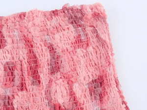 Detalle de la textura de tela fruncida rosa con capas elásticas en un vestido corto