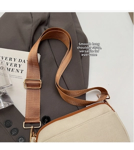 Detail of light beige crossbody bag with adjustable brown nylon strap on a grey blazer