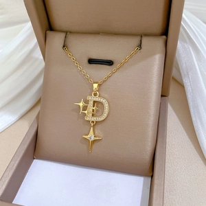Close-up of gold starburst and 'D' pendant with pavé zircons in a jewelry box