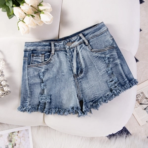 Dettaglio ravvicinato di pantaloncini di jeans blu strappati con orli sfrangiati su fondo bianco