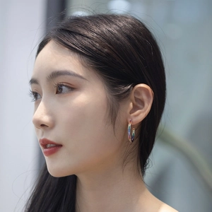 Close-up of a model wearing a C-shaped silver earring with rainbow zirconia crystals