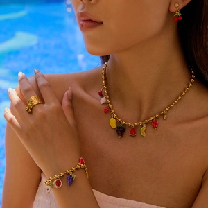 Golden titanium steel jewelry set featuring colorful fruit pendants by a blue pool