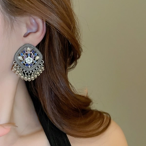 Macro detail of ethnic silver rhombus earrings with floral enamel and mini bells