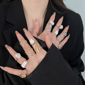Close-up of minimalist gold and silver rings with pearls worn by model on black suit