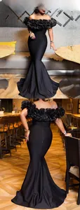 Detail view of ruffle off-shoulder neckline and back zipper on black fishtail dress
