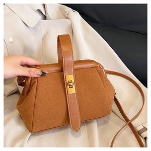 Detail of brown suede shell bag with golden metal lock and leather handle on a trench coat