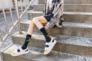 Detail of crew socks with green and grey abstract animal print worn with white sandals