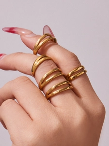 Close-up of minimalist double-layer gold stainless steel rings on hand over lilac background