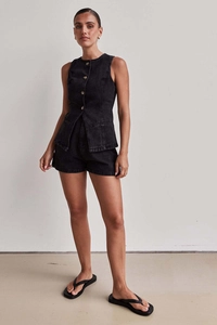 Dettaglio del completo in denim nero senza maniche con trama in cotone e bottoni frontali