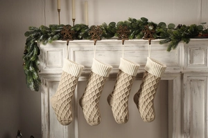 Makroaufnahme von gestrickten Weihnachtsstrümpfen in Beige und Khaki am Kamin hängend