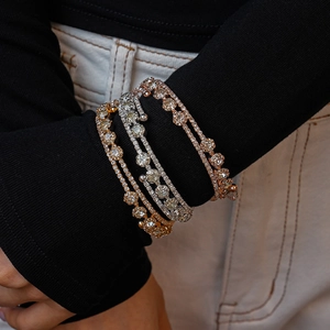 Close-up of triple-layered cubic zirconia open bracelets in gold, silver and rose gold