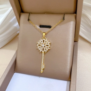 Macro detail of luxury gold flower key pendant with sparkling cubic zirconia inlay