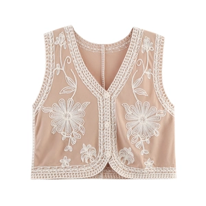 Detail of apricot V-neck vest featuring white floral embroidery and delicate lace trim