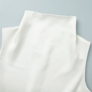 Detailed close-up of white satin high-neck top showing delicate lace trim and smooth fabric