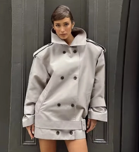 Detail of light gray double-breasted trench jacket with oversized silhouette and lapels