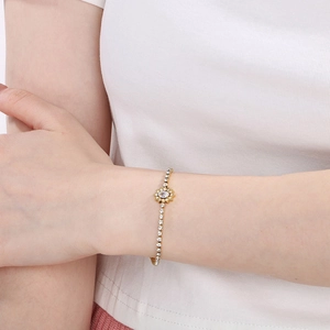 Detail view of a gold titanium steel bracelet with sunflower rhinestone on a model's wrist