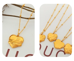 Detailed view of gold 18K plated heart hugging pendant on elegant satellite beaded chain