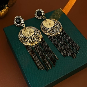 Detail of vintage gold coin earrings with portrait relief and black chain tassels