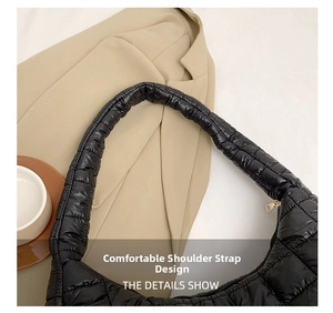Detail of wide quilted shoulder strap and square stitching on black nylon bag