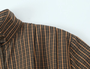 Detailed view of the yellow plaid cotton shirt collar and pleated shoulder stitching
