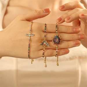 Detailed view of three gold bracelets with insect charms and colorful gemstones on a wrist