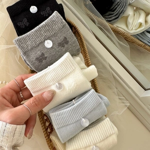 Détail de chaussettes en coton côtelé avec boutons nœuds en cinq couleurs douces