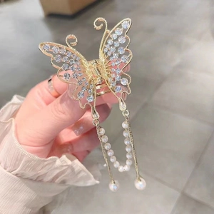 Close-up of golden metal butterfly hair claw with rhinestones and pearl tassels