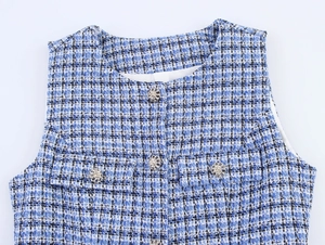 Vue détaillée de la texture en tweed bleu et des boutons métalliques en forme de fleur