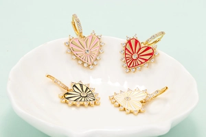 Detail of four enamel heart earrings in pink, red, black, and white with gold finish