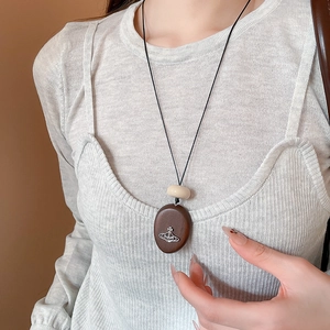 Detail of wooden oval planet pendant necklace worn by a model in vintage ethnic style