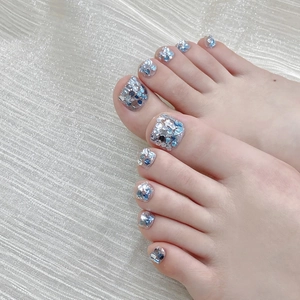Handmade sparkly blue and silver glitter press-on toenails on textured fabric