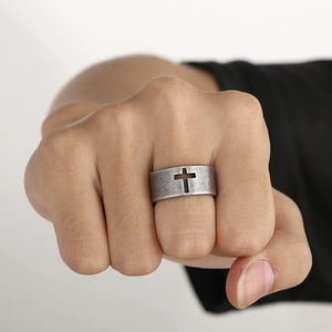 Close-up of wide retro stainless steel ring with hollow cross on man's clenched fist