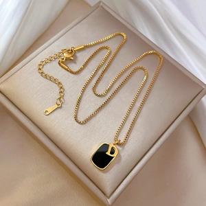 Detailed macro view of gold-plated titanium necklace with square D pendant and S.STEEL tag