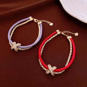 Detailed shot of double-layer woven leather bracelets with gold-plated zircon X-cross charms